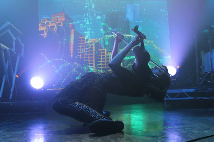A dynamic HD wallpaper featuring Lindsey Stirling performing passionately on stage, illuminated by vibrant lights and a colorful backdrop.