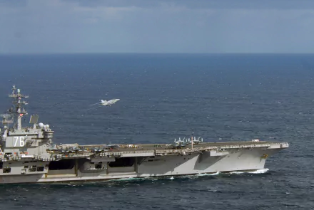 Aircraft carrier USS Ronald Reagan (CVN-76) with a McDonnell Douglas F/A-18 Hornet launching over open ocean, captured in stunning 4K Ultra HD detail.