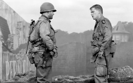 A striking black and white image featuring Matt Damon and Tom Hanks in a scene from Saving Private Ryan, depicting intense dialogue amidst a war-torn backdrop.