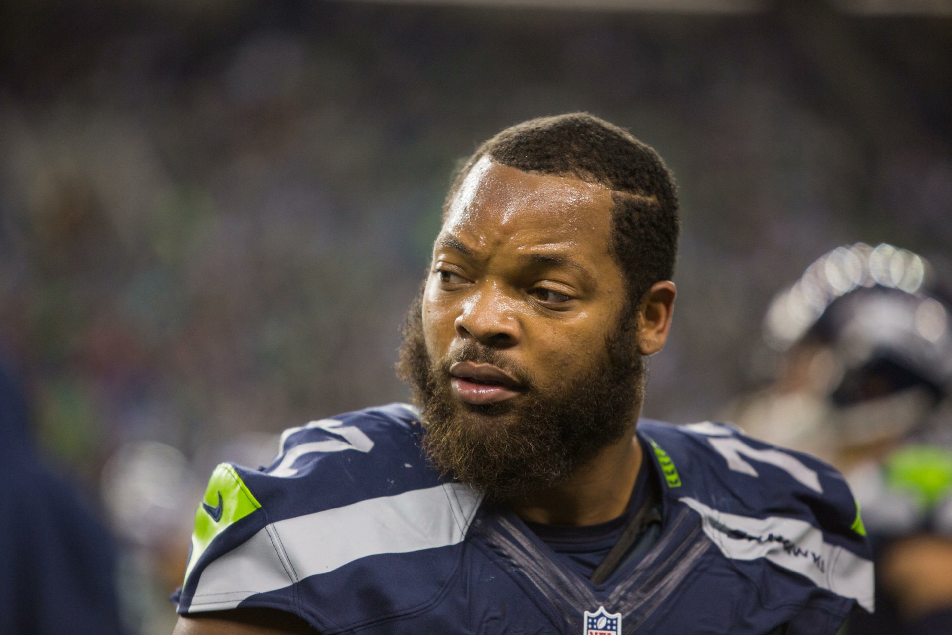 Close-up of a Seattle Seahawks football player in uniform on the sidelines, gritty sports portrait rendered as a 2K Quad HD PC desktop wallpaper and background.