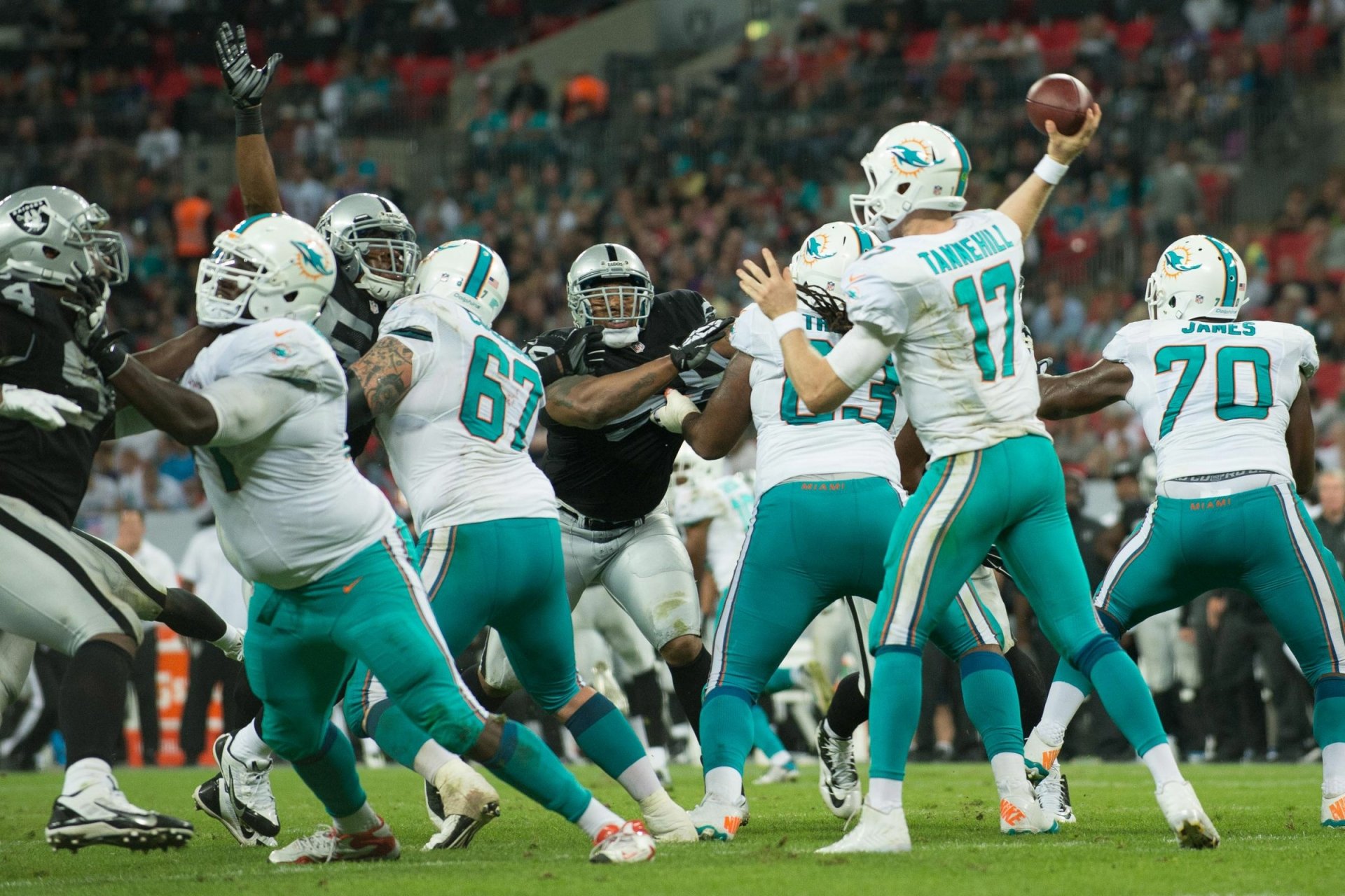 HD PC desktop wallpaper showcasing Miami Dolphins players during a live NFL game, highlighting intense on-field action in vibrant team colors.