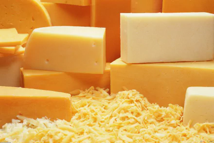 HD PC desktop wallpaper and background showing a close-up food shot of assorted blocks and shredded yellow cheese, rich texture and warm tones.