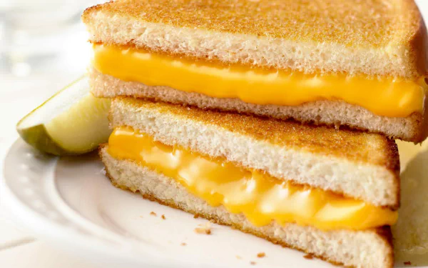 Close-up of a grilled cheese sandwich with melted cheddar cheese on a plate, captured in high definition as a PC desktop wallpaper background.