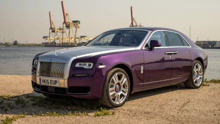 HD desktop wallpaper featuring a luxurious Rolls-Royce Ghost car in a striking purple color, parked near a waterfront with industrial cranes in the background.