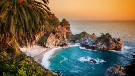 HD desktop wallpaper of a stunning Big Sur coastline at sunset, featuring a secluded beach surrounded by rocky cliffs and vibrant greenery.
