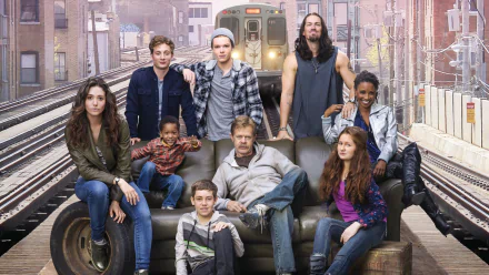 A vibrant HD wallpaper featuring the cast of the TV show Shameless. The characters pose together on a couch with a backdrop of an urban train setting, capturing the show's unique spirit.
