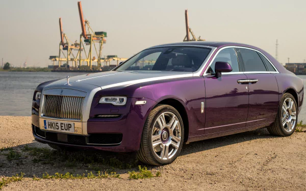 HD desktop wallpaper featuring a luxurious Rolls-Royce Ghost car in a striking purple color, parked near a waterfront with industrial cranes in the background.