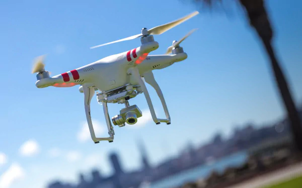 A close-up view of a drone flying against a clear blue sky, with a city skyline in the background. This image serves as a vibrant HD PC desktop wallpaper and background.