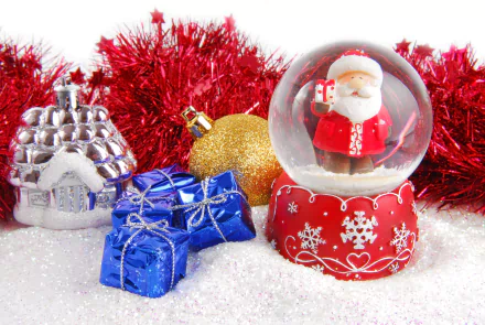 A 4K Ultra HD desktop wallpaper featuring a festive Christmas snow globe with Santa, surrounded by holiday ornaments and red tinsel on a snowy surface.