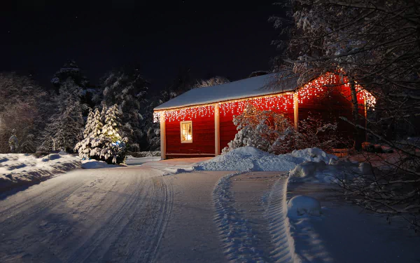 HD PC desktop wallpaper/background: winter scene of a man-made red cabin lit with holiday lights, snow-covered trees and a snowy lane.