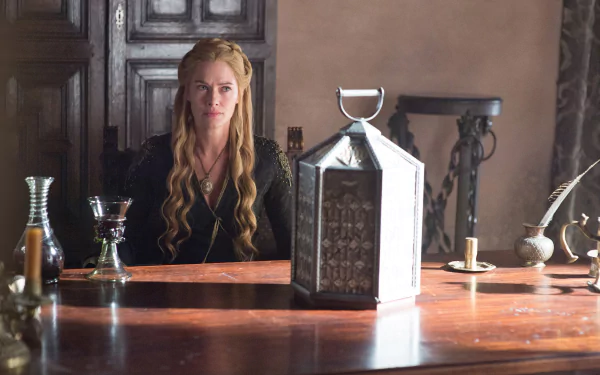 Cersei Lannister, portrayed by Lena Headey in the TV show Game of Thrones, sits at a wooden table in a dimly lit room, captured in HD for a PC desktop wallpaper.