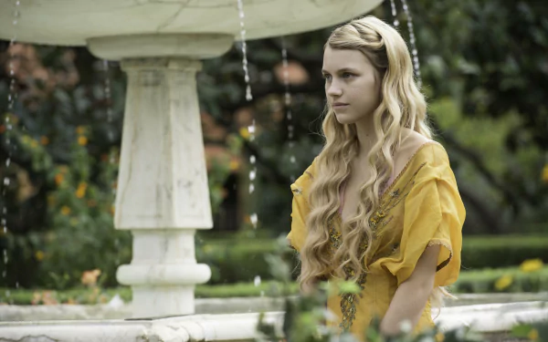 Nell Tiger Free as Myrcella Baratheon from Game of Thrones stands near a fountain in a lush garden, captured in a 4K Ultra HD TV show wallpaper.