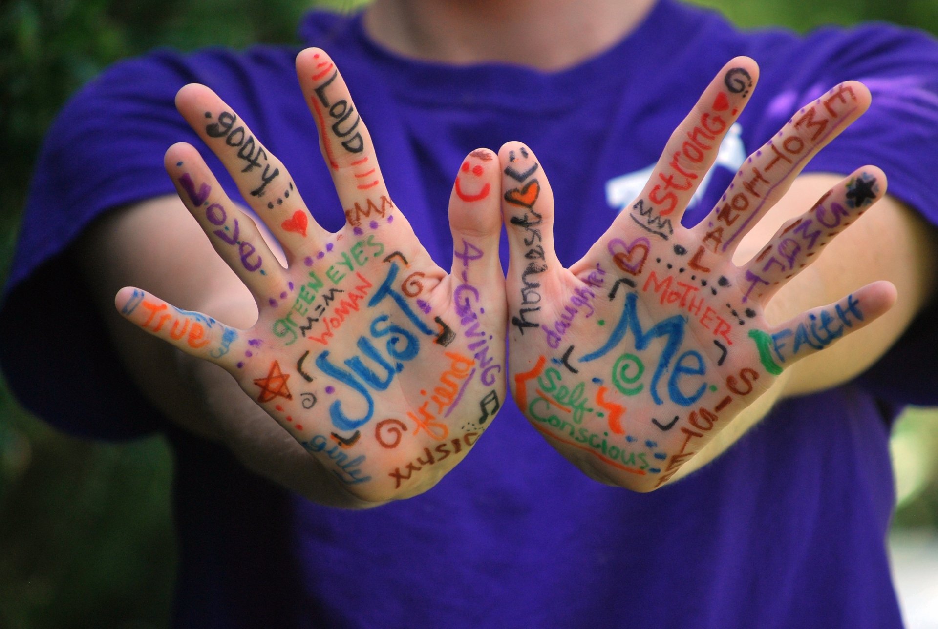 Close-up of colorful words and drawings on hands against a blurred background, captured in vibrant HD photography for a PC desktop wallpaper and background.