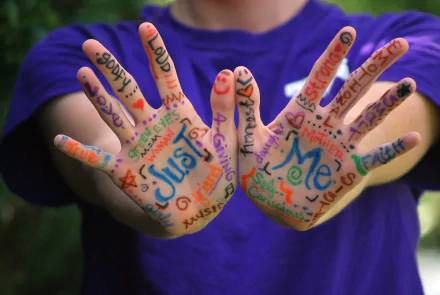Close-up of colorful words and drawings on hands against a blurred background, captured in vibrant HD photography for a PC desktop wallpaper and background.