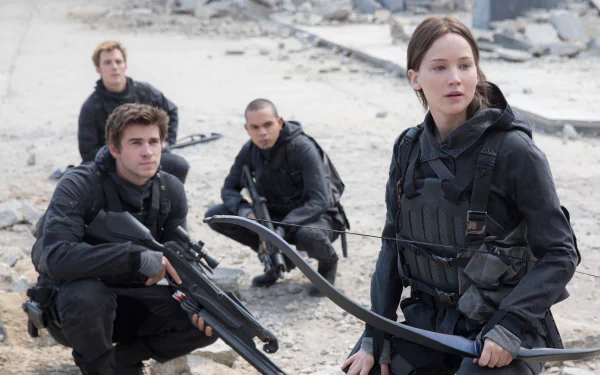 4K Ultra HD wallpaper featuring Jennifer Lawrence and Liam Hemsworth in The Hunger Games: Mockingjay - Part 2, dressed in tactical gear amid a ruined landscape.