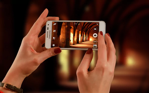 A person holding a Samsung phone capturing a well-lit, man-made corridor, showcased in 4K Ultra HD quality as a PC desktop wallpaper background.