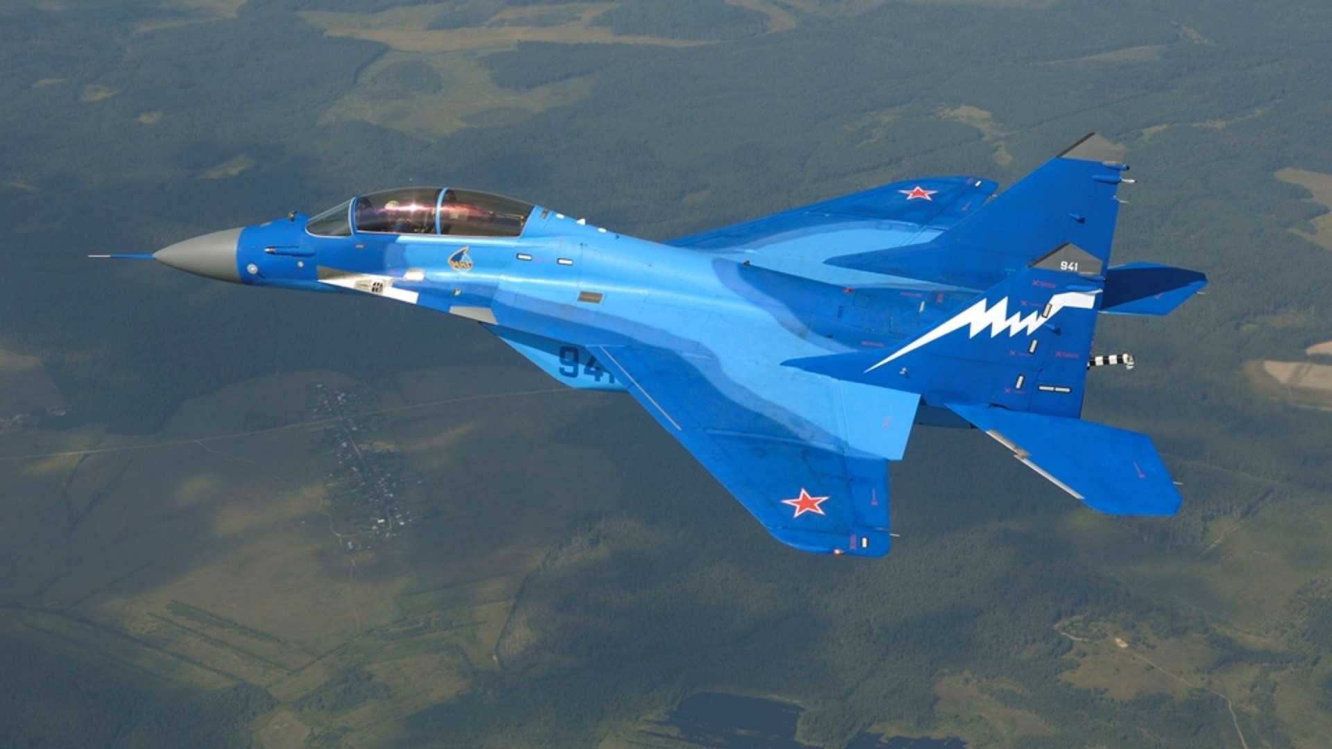 A striking Mikoyan MiG-29 jet fighter in vibrant blue, soaring over lush landscapes, showcasing its military prowess as an impressive air force aircraft.