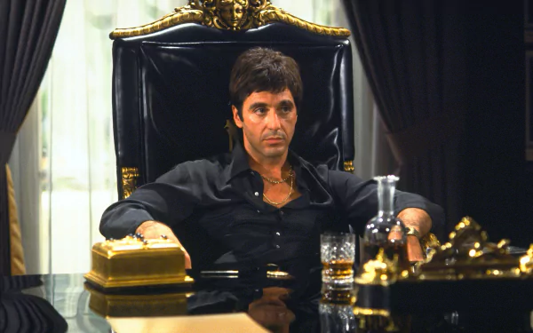 Al Pacino as Tony Montana in a classic scene from Scarface, seated in an opulent chair, exuding power and intensity. 4K Ultra HD desktop wallpaper capturing cinematic brilliance.