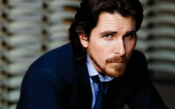 HD desktop wallpaper featuring a close-up portrait of actor Christian Bale in a dark suit, showcasing his intense gaze against a blurred background.