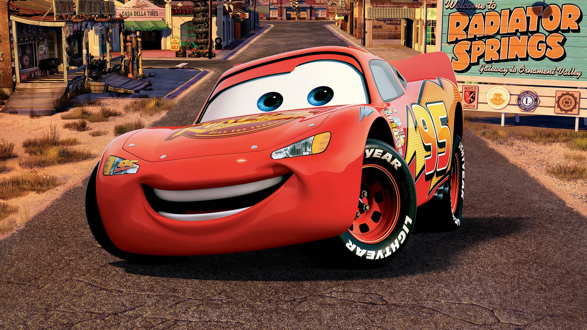 HD PC desktop wallpaper featuring Lightning McQueen from the movie Cars (Pixar) smiling on the road in Radiator Springs.