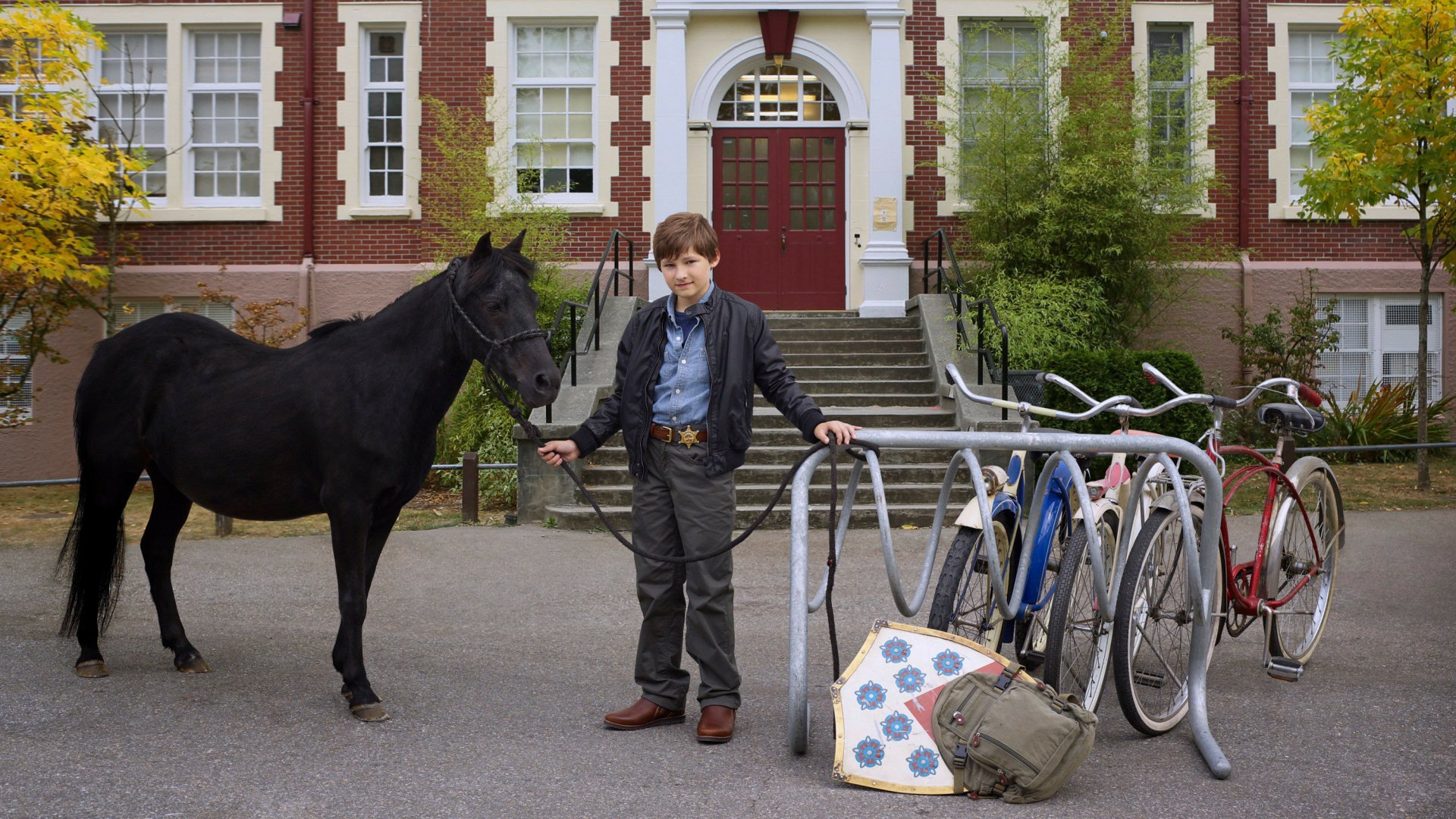 Henry Mills from the TV show Once Upon A Time stands holding a black horse outside a brick building, featured in an HD PC desktop wallpaper and background.