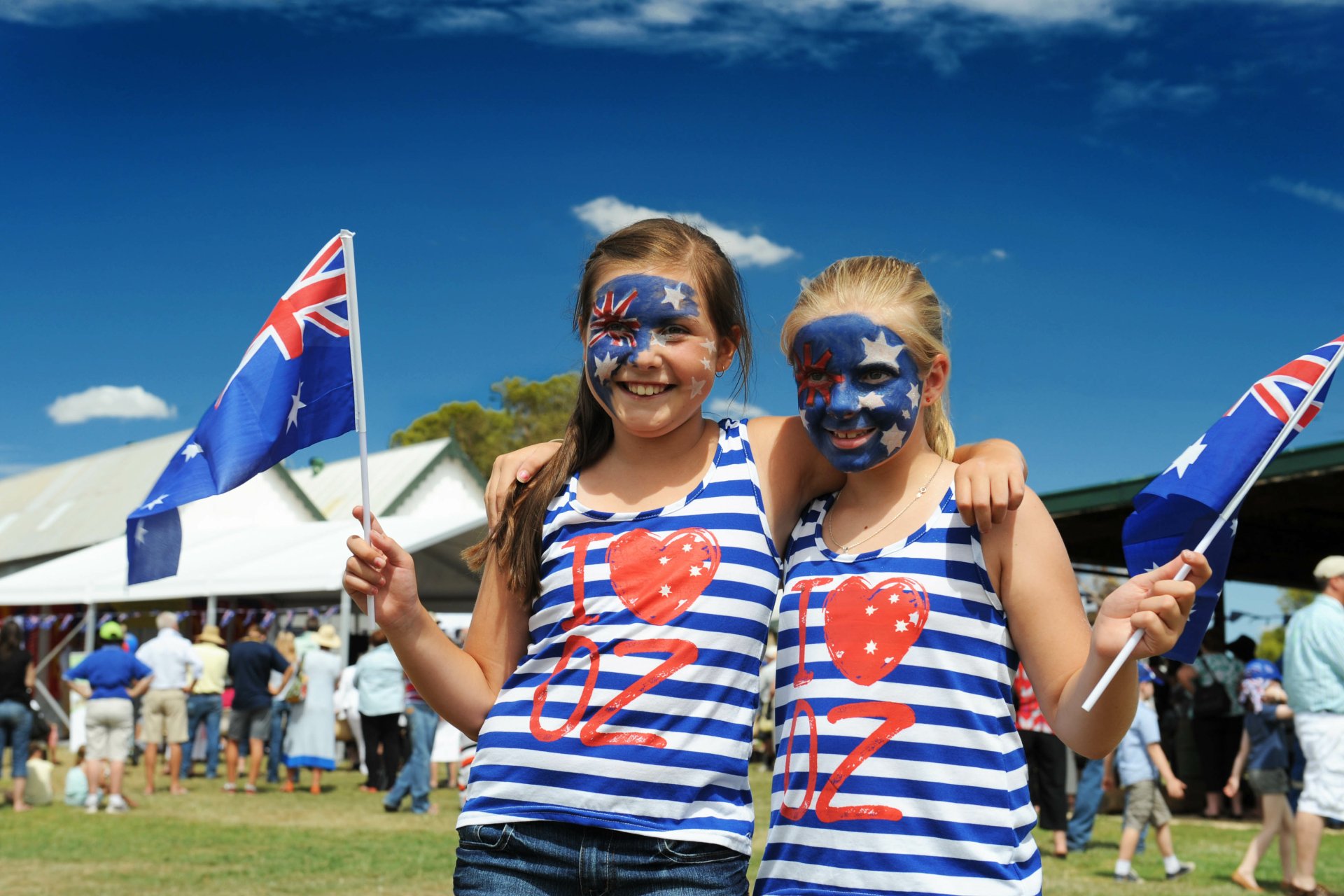 Two girls with face paint and holding Australian flags celebrate Australia Day outdoors under a bright blue sky, captured in 4K Ultra HD for a PC desktop wallpaper.