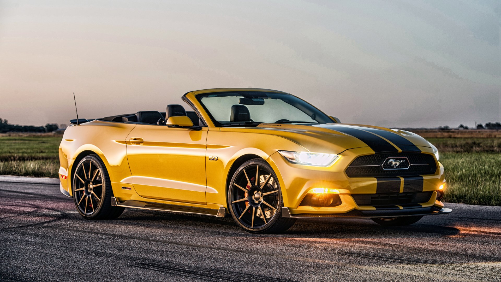 Yellow Ford Mustang GT muscle car convertible with black racing stripes parked on a road at sunset, captured in striking 4K Ultra HD desktop wallpaper quality.