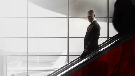 A dramatic HD wallpaper featuring Agent 47 from the video game Hitman (2016), capturing his iconic presence as he descends an escalator in a sleek, modern environment.