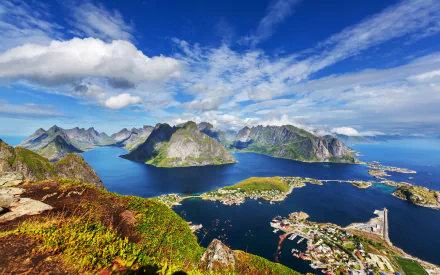 A stunning HD aerial view of the town of Reine, nestled between ocean and lakes, surrounded by majestic mountains in Lofoten. The vibrant landscape captures the beauty of nature.