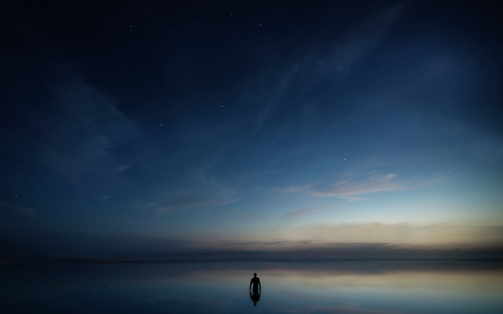 Silhouette of a person standing by a calm body of water reflecting a starry sky and natural twilight, captured in an HD desktop wallpaper background.