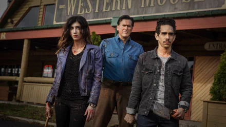 TV show Ash vs. Evil Dead 2K Quad HD PC desktop wallpaper: three blood-smeared protagonists stand grimly before a Western saloon, weapons at the ready.