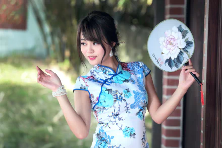 An Asian woman with brown eyes and brunette hair poses with an oriental fan, wearing a floral dress, with a bokeh effect background. HD desktop wallpaper and background.