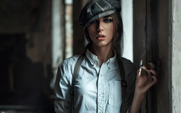 A brunette model wearing a hat stands confidently in a dimly lit space, smoking. The bokeh effect enhances the mood, creating an evocative HD wallpaper background.