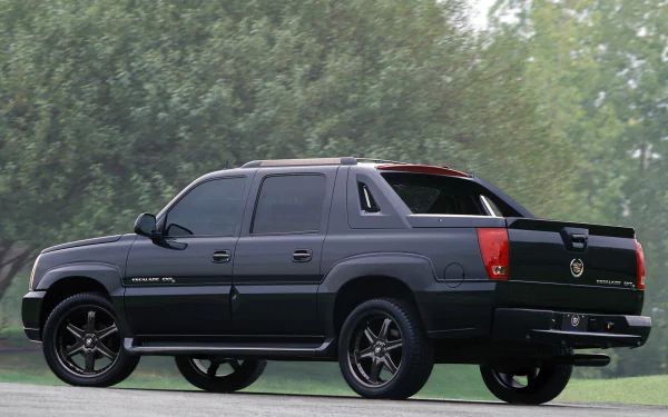 HD PC desktop wallpaper of a black Cadillac Escalade EXT vehicle parked by trees, shown from a rear three-quarter view.