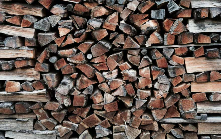 HD desktop wallpaper featuring a stack of chopped wood logs with a textured appearance.