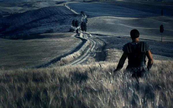A gladiator stands in a serene landscape, gazing at a winding path that stretches across rolling hills. HD desktop wallpaper and background from the movie Gladiator.