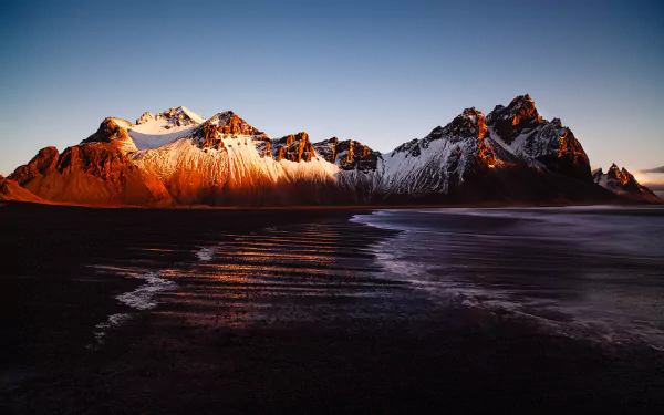 Stunning view of Vestrahorn Mountain in Iceland, featuring dramatic peaks and serene sandy landscapes, captured during soft light for a breathtaking nature backdrop.