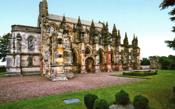 HD desktop wallpaper showcasing the intricate architecture of Rosslyn Chapel, a historic religious building in Scotland surrounded by lush greenery.