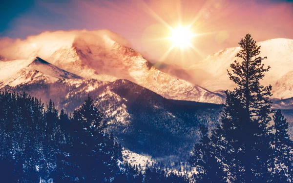 A vibrant 4K Ultra HD desktop wallpaper showcasing sunbeams over rocky mountains, with a dense forest in the foreground under a colorful sky.