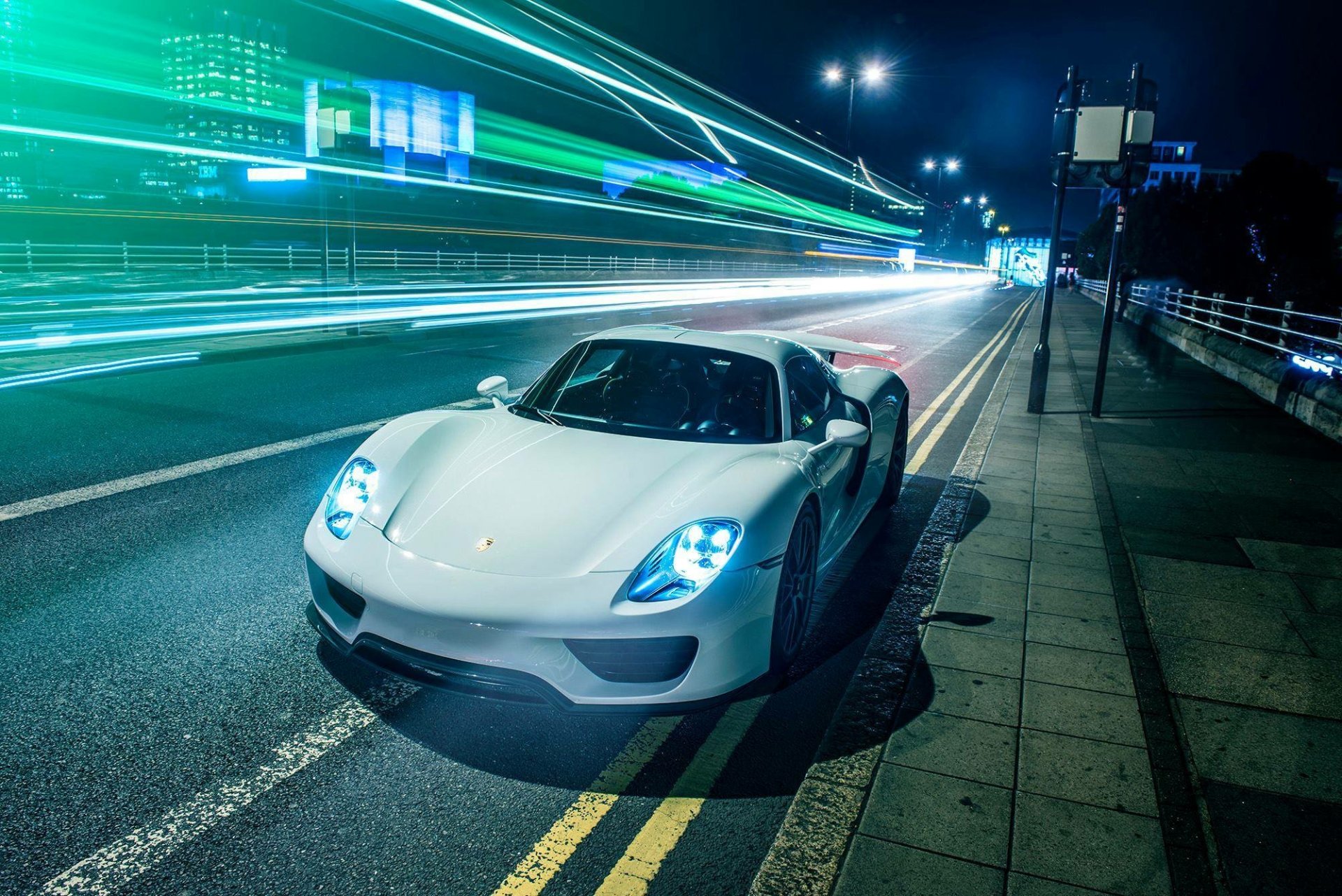 White Porsche 918 Spyder supercar parked on a city street at night with vibrant light trails, captured in HD for a dynamic PC desktop wallpaper and background.