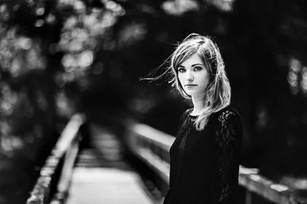 Black and white HD desktop wallpaper featuring a woman model standing on a bridge with a blurred bokeh background.