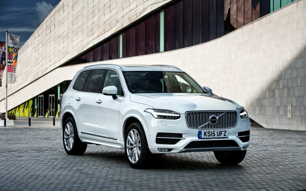 White Volvo XC90 SUV parked on a modern cobblestone street with a contemporary architectural building in the background, captured in HD for a desktop wallpaper.