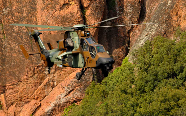 HD PC desktop wallpaper and background showing a Eurocopter Tiger attack helicopter in military camouflage flying near rocky cliffs.