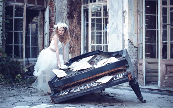Blonde bride model in a wedding dress leans over a broken piano strewn with sheet music in a ruined courtyard — HD PC desktop wallpaper and background
