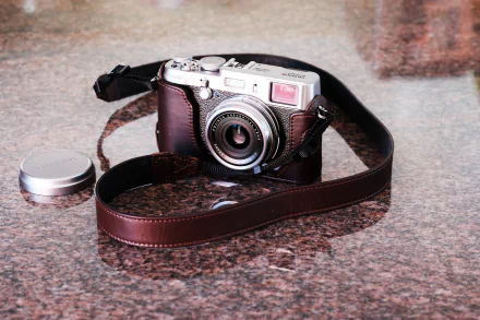 HD PC desktop wallpaper featuring a Fujifilm man-made camera with a brown leather strap resting on a polished surface.