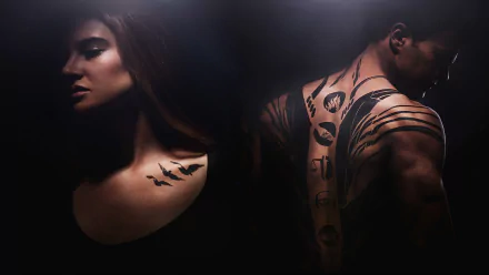 A striking HD wallpaper from the movie Divergent, featuring a woman in profile with a bird tattoo and a man showcasing intricate back tattoos, set against a dramatic dark background.
