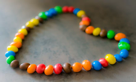 A heart shape formed from colorful M&M's candy pieces on a surface, captured in 4K Ultra HD as a vibrant PC desktop wallpaper.