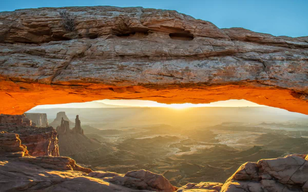 Sunny landscape through Mesa Arch framing a glowing canyon at sunrise — nature scene, HD PC desktop wallpaper and background.