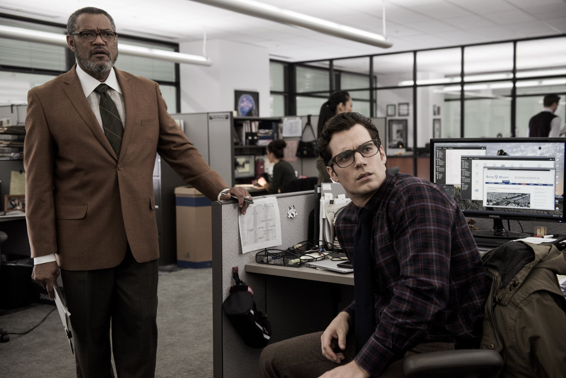Superman and Clark Kent, portrayed by Henry Cavill, interact in the Daily Planet office, with Perry White, played by Laurence Fishburne, in this scene from *Batman V Superman: Dawn Of Justice*.