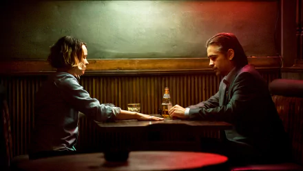 Rachel McAdams and Colin Farrell share a tense moment in a dimly lit bar setting from the TV show True Detective, capturing a gripping scene of drama and intrigue.